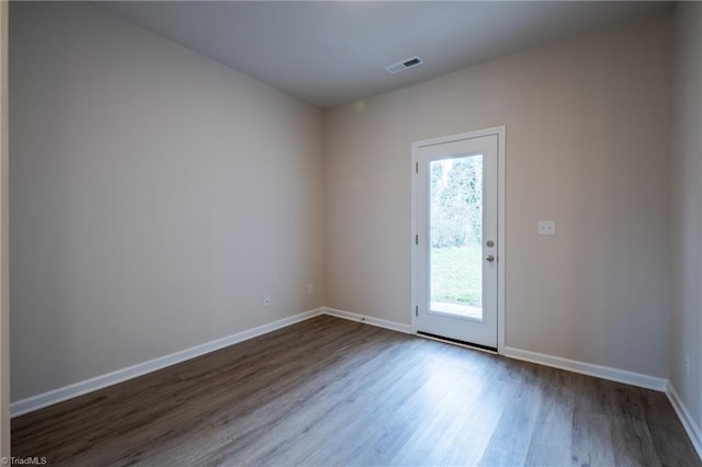 empty room featuring dark wood-style floors, baseboards, and visible vents