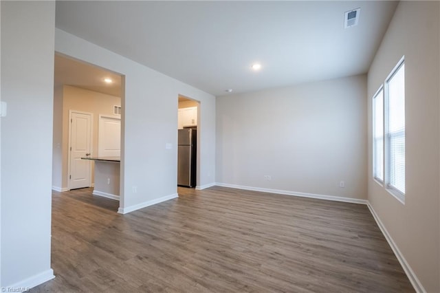 spare room with recessed lighting, wood finished floors, visible vents, and baseboards