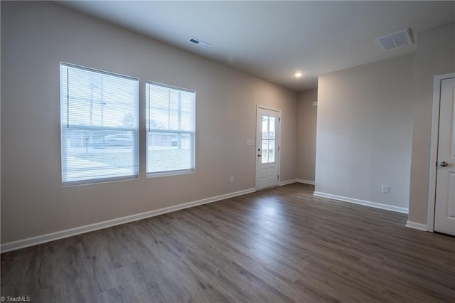 unfurnished room featuring baseboards, visible vents, dark wood finished floors, and recessed lighting