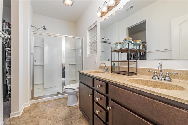 5838 Springer Dr, Greensboro, NC 27405 - bathroom with a stall shower, toilet, double vanity, a walk in closet, and baseboards