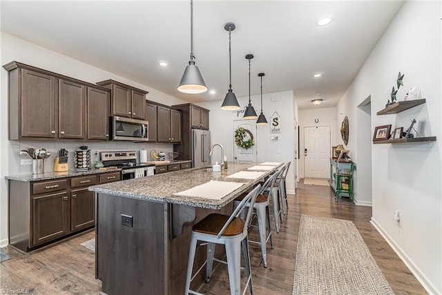 5838 Springer Dr, Greensboro, NC 27405 - kitchen with stainless steel appliances, dark brown cabinets, a kitchen bar, a center island with sink, and dark wood-style floors