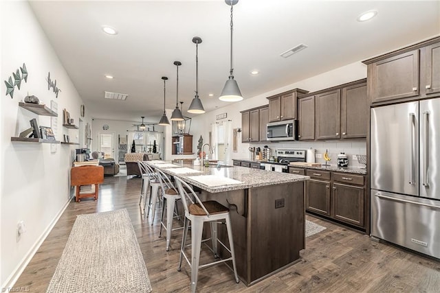 5838 Springer Dr, Greensboro, NC 27405 - kitchen featuring appliances with stainless steel finishes, dark brown cabinetry, a sink, dark wood-type flooring, and recessed lighting