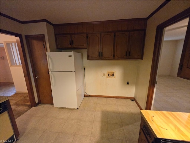 kitchen with dark brown cabinets, a textured ceiling, white fridge, crown molding, and butcher block countertops