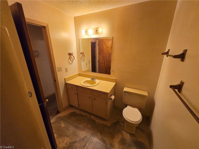 bathroom featuring a textured ceiling, vanity, and toilet