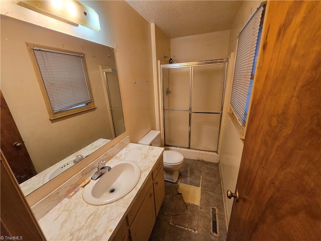 bathroom featuring vanity, a textured ceiling, tile patterned floors, walk in shower, and toilet