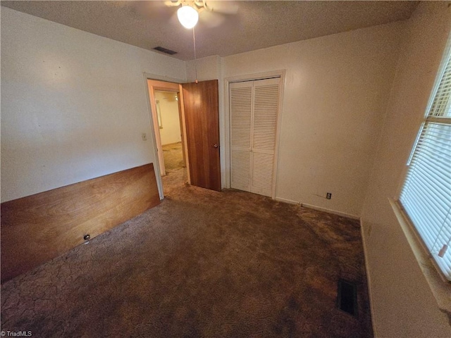 unfurnished bedroom with ceiling fan, a textured ceiling, a closet, and carpet