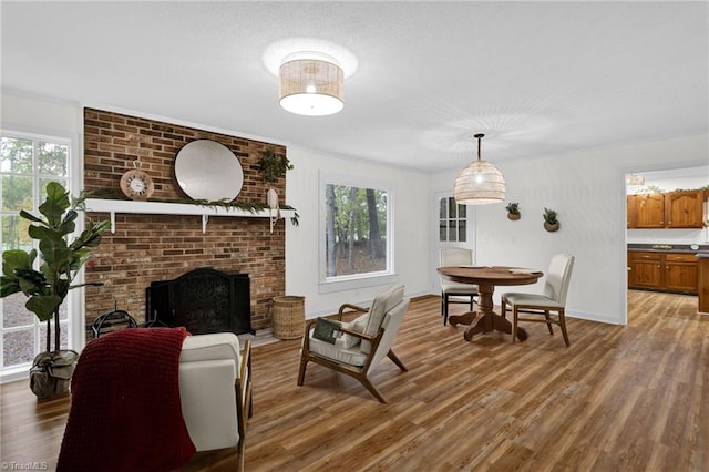 living room with wood-type flooring, a brick fireplace, and a healthy amount of sunlight