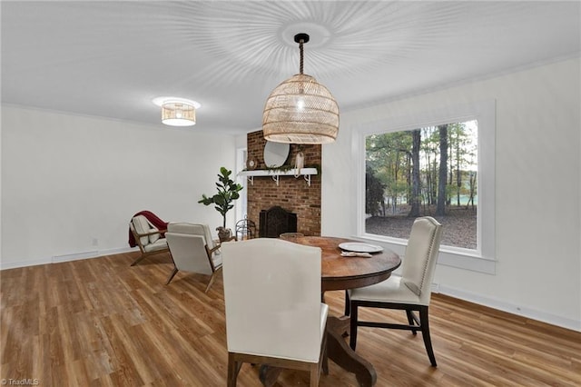 dining room featuring hardwood / wood-style flooring and a brick fireplace