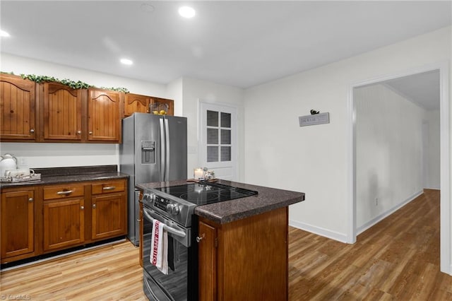 kitchen with appliances with stainless steel finishes, a center island, and light hardwood / wood-style flooring