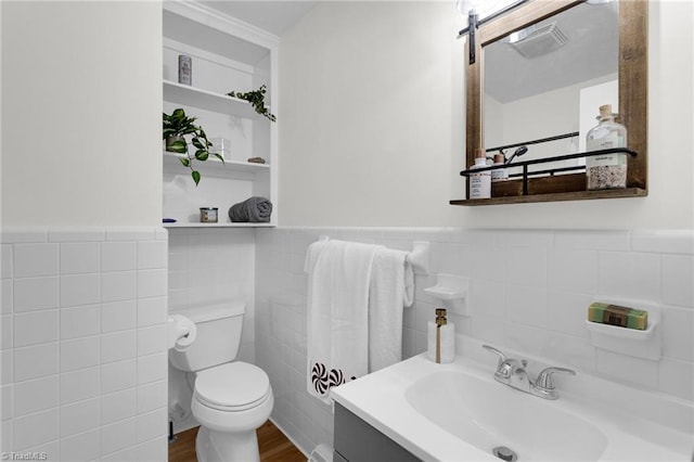 bathroom with built in features, tile walls, vanity, wood-type flooring, and toilet