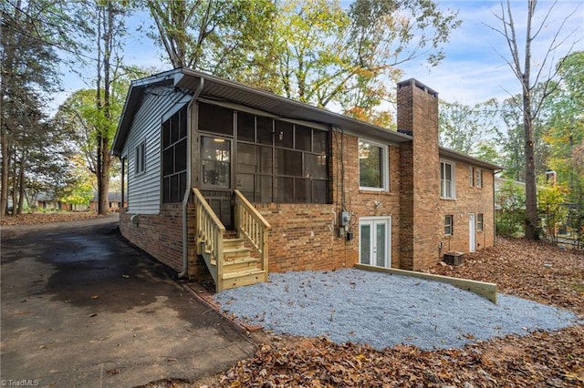 back of property featuring a sunroom and central AC