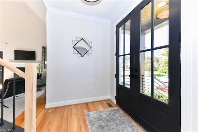 foyer featuring hardwood / wood-style floors, crown molding, and french doors