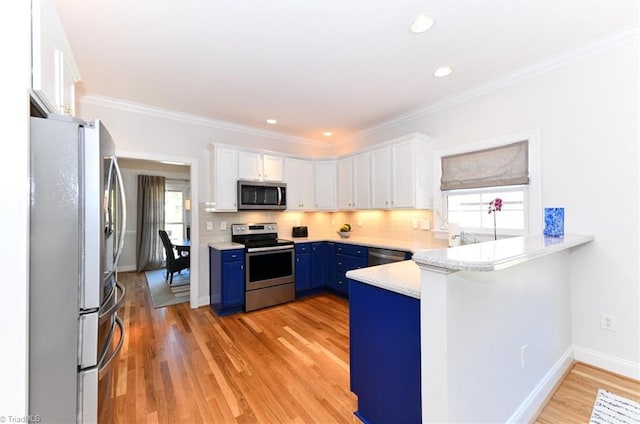 kitchen featuring white cabinets, blue cabinets, and appliances with stainless steel finishes