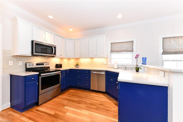 kitchen featuring blue cabinetry, white cabinetry, light hardwood / wood-style flooring, appliances with stainless steel finishes, and ornamental molding