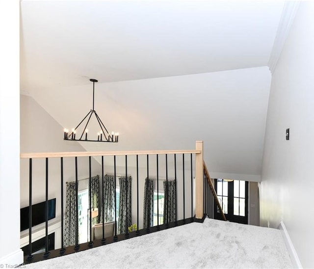 stairway featuring plenty of natural light, ornamental molding, lofted ceiling, and an inviting chandelier