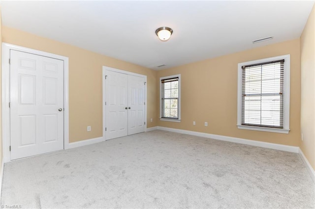 unfurnished bedroom featuring light colored carpet and multiple windows