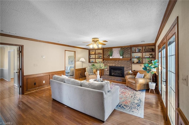 living room with ornamental molding, a brick fireplace, and hardwood / wood-style floors