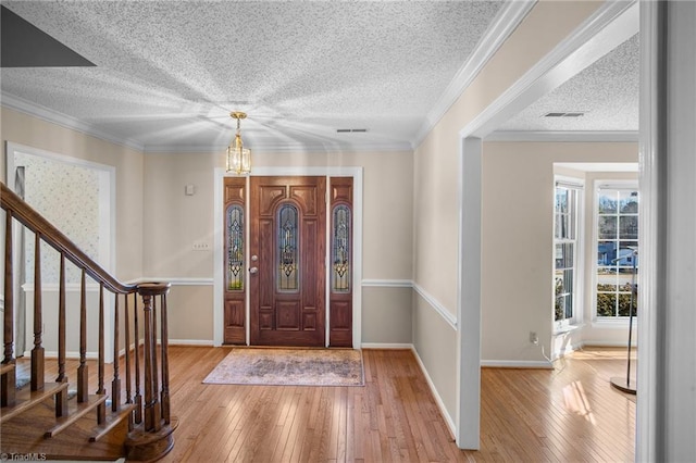 foyer with crown molding, light hardwood / wood-style floors, and a textured ceiling