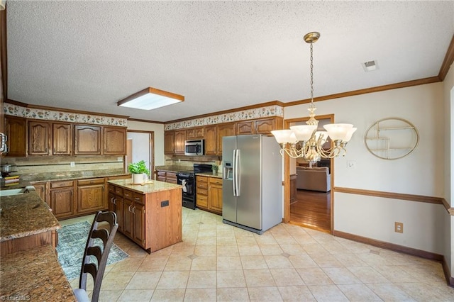 kitchen with crown molding, appliances with stainless steel finishes, a center island, a notable chandelier, and decorative light fixtures