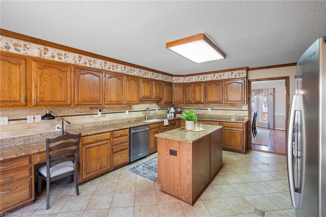 kitchen featuring a kitchen island, appliances with stainless steel finishes, ornamental molding, light stone counters, and a textured ceiling