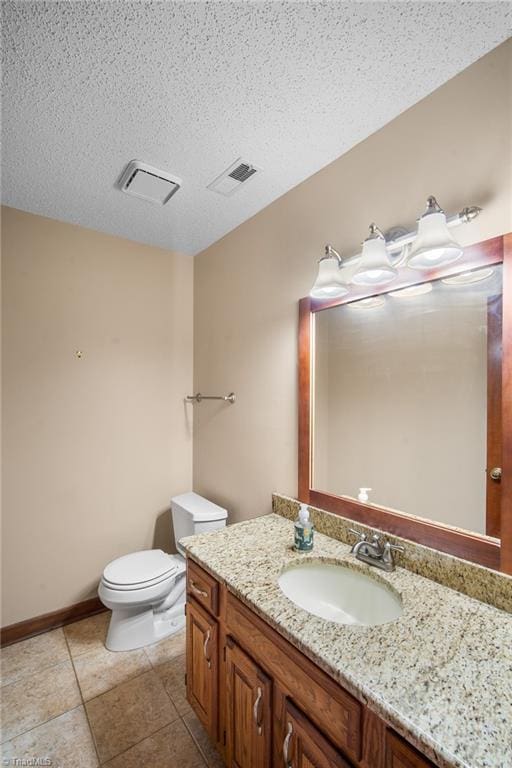 bathroom with vanity, toilet, tile patterned flooring, and a textured ceiling