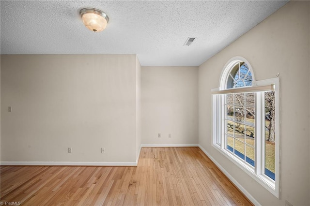 empty room with a textured ceiling and light wood-type flooring