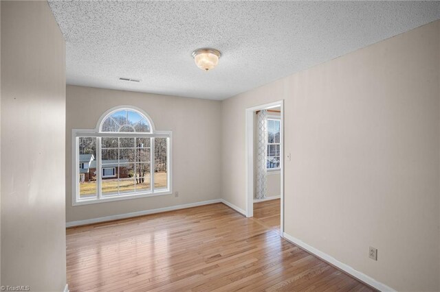 unfurnished room featuring light hardwood / wood-style floors and a textured ceiling