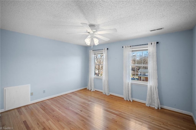 empty room with a textured ceiling, ceiling fan, and light wood-type flooring