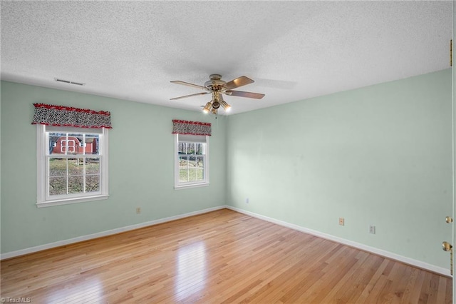 unfurnished room with ceiling fan, light hardwood / wood-style flooring, and a textured ceiling