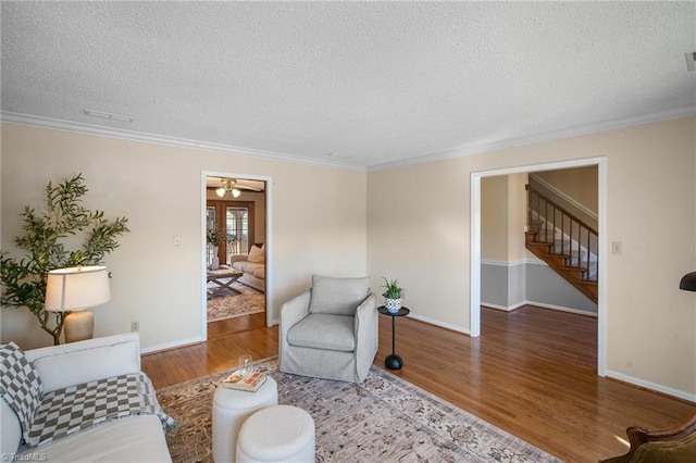 living room with ornamental molding, wood-type flooring, and a textured ceiling