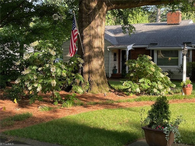 exterior space with a front yard, roof with shingles, and a chimney