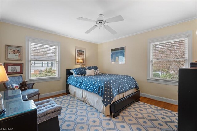 bedroom featuring baseboards, wood finished floors, and ornamental molding