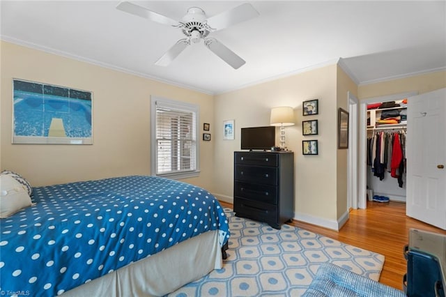 bedroom with ornamental molding, wood finished floors, a closet, baseboards, and a spacious closet