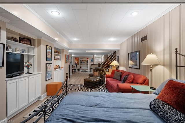 living area with stairs, visible vents, light wood-style floors, and crown molding