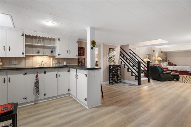 kitchen with dark countertops, open shelves, open floor plan, and light wood finished floors