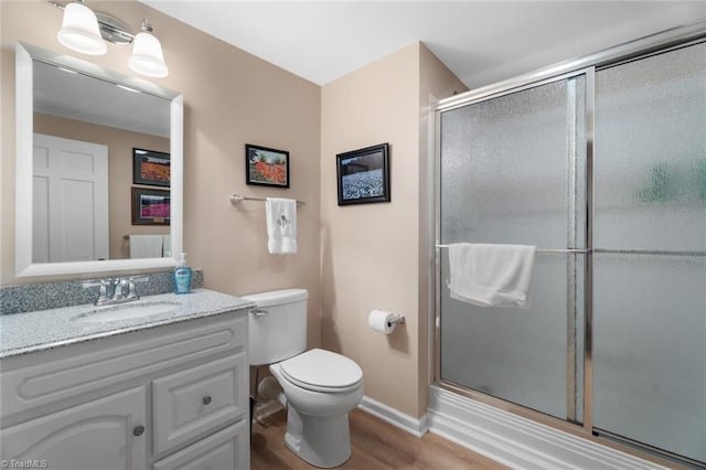 full bath with a shower with door, baseboards, toilet, wood finished floors, and vanity