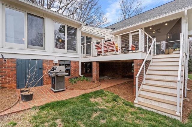 back of property with brick siding, a shingled roof, stairs, and a patio area