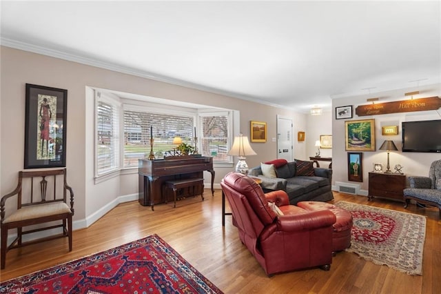 living room with crown molding, light wood-style flooring, baseboards, and visible vents