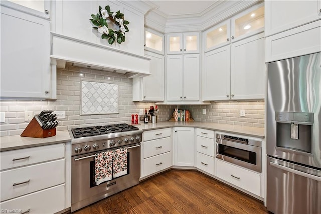 kitchen with light countertops, white cabinetry, appliances with stainless steel finishes, and glass insert cabinets