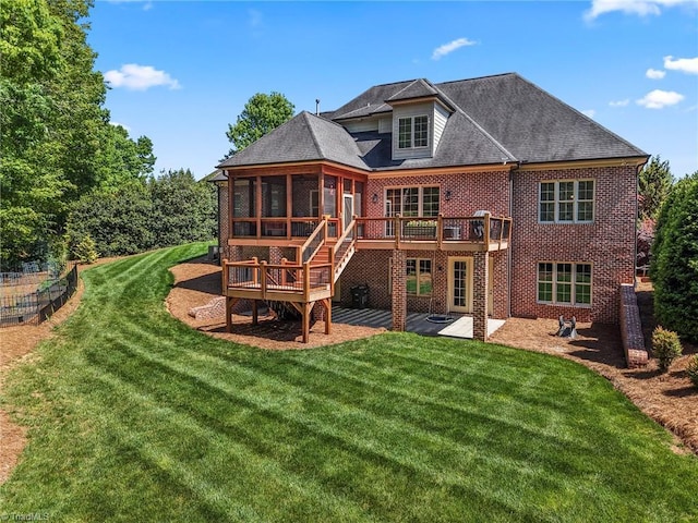 back of property featuring brick siding, a sunroom, a deck, a patio area, and a yard