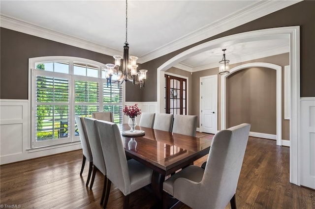 dining space with an inviting chandelier, arched walkways, a decorative wall, and a healthy amount of sunlight