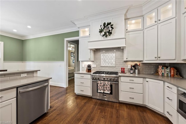 kitchen featuring appliances with stainless steel finishes, dark wood finished floors, a wainscoted wall, white cabinetry, and ornamental molding