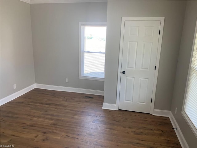 unfurnished room with baseboards and dark wood-style flooring