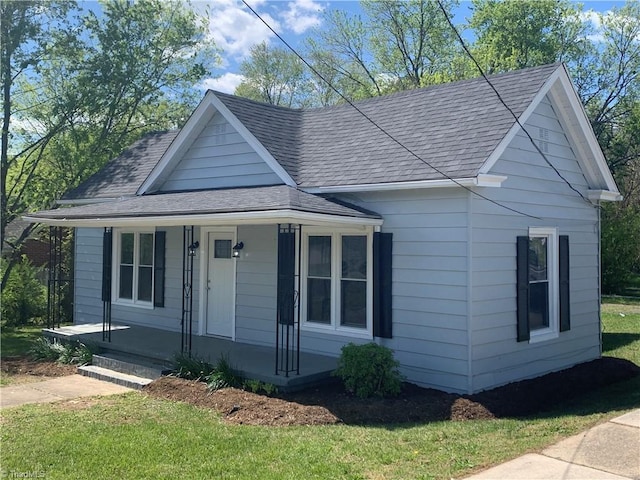 view of front facade with a porch, a shingled roof, and a front yard