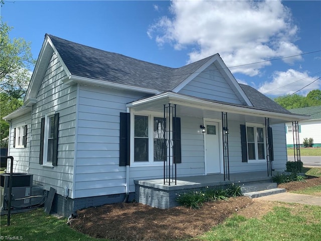 view of front facade featuring roof with shingles, a porch, crawl space, and central AC unit