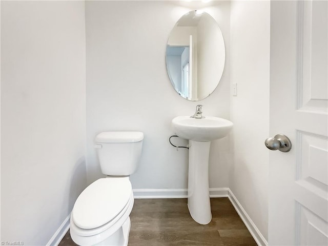 bathroom with toilet, baseboards, and wood finished floors