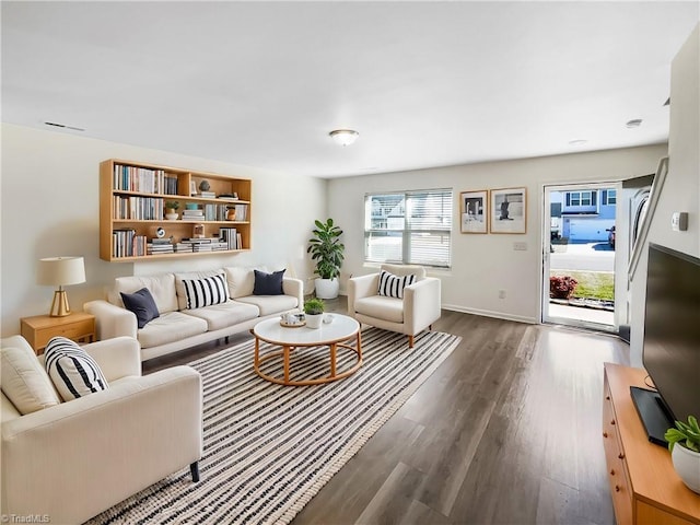 living area featuring baseboards and dark wood-style flooring