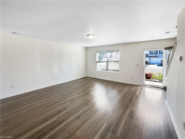 unfurnished living room with visible vents, baseboards, and dark wood-style flooring