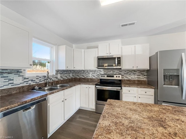 kitchen with a sink, stainless steel appliances, visible vents, and white cabinetry