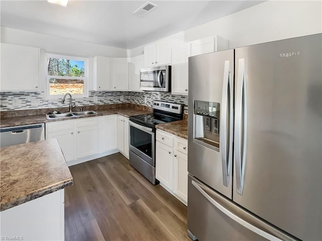 kitchen featuring visible vents, dark wood-type flooring, decorative backsplash, appliances with stainless steel finishes, and a sink